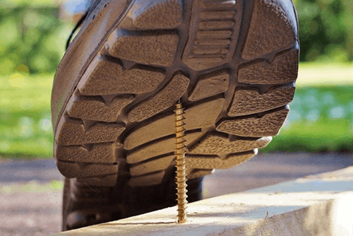 A boot stepping on a metal screw.