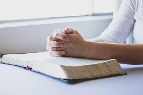 A person praying with the bible open.