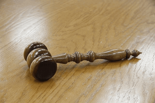 A dark wooden judges mallet on a wooden table.