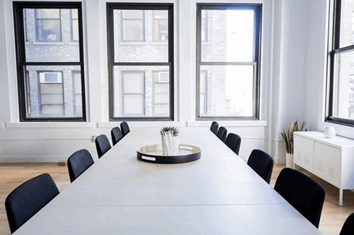 An empty meeting room with tables and chairs set up.