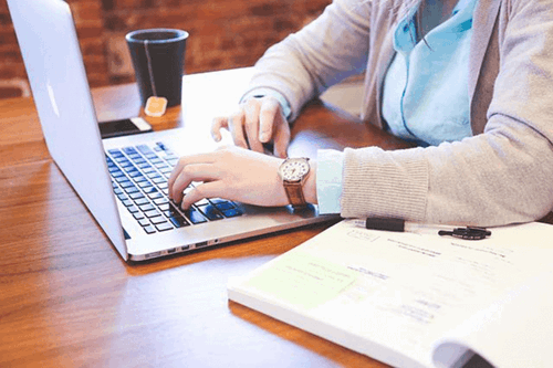 an employee working on a laptop with a notebook