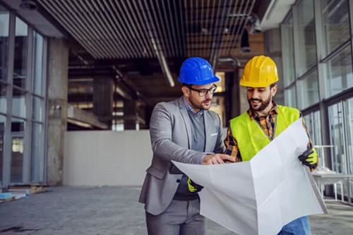 two employers looking a plans whil ewearing hard hats