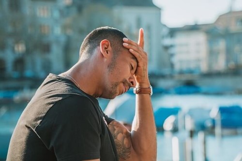 A man with his head in his hands, looking stressed.